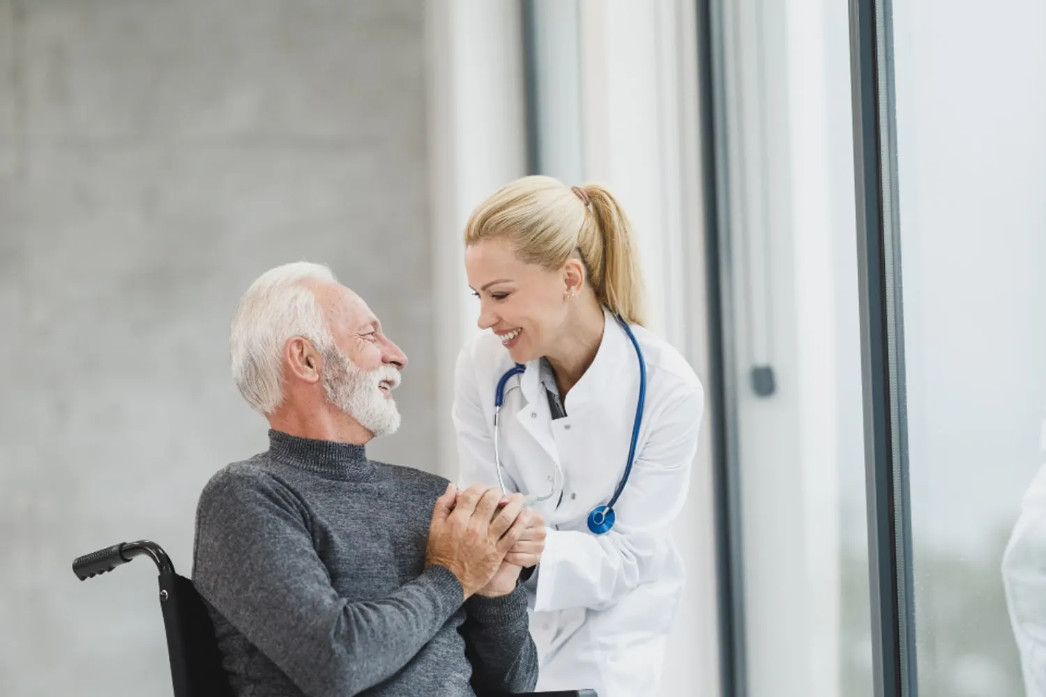 Homem idoso sentado em cadeira de rodas conversando com profissional de saúde